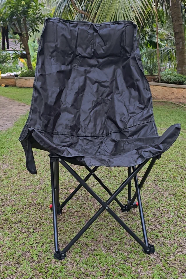 Front view of the open black folding chair standing on grass, with no person seated.