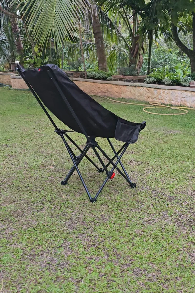 The black chair standing alone on a lawn beneath palms and garden greenery.